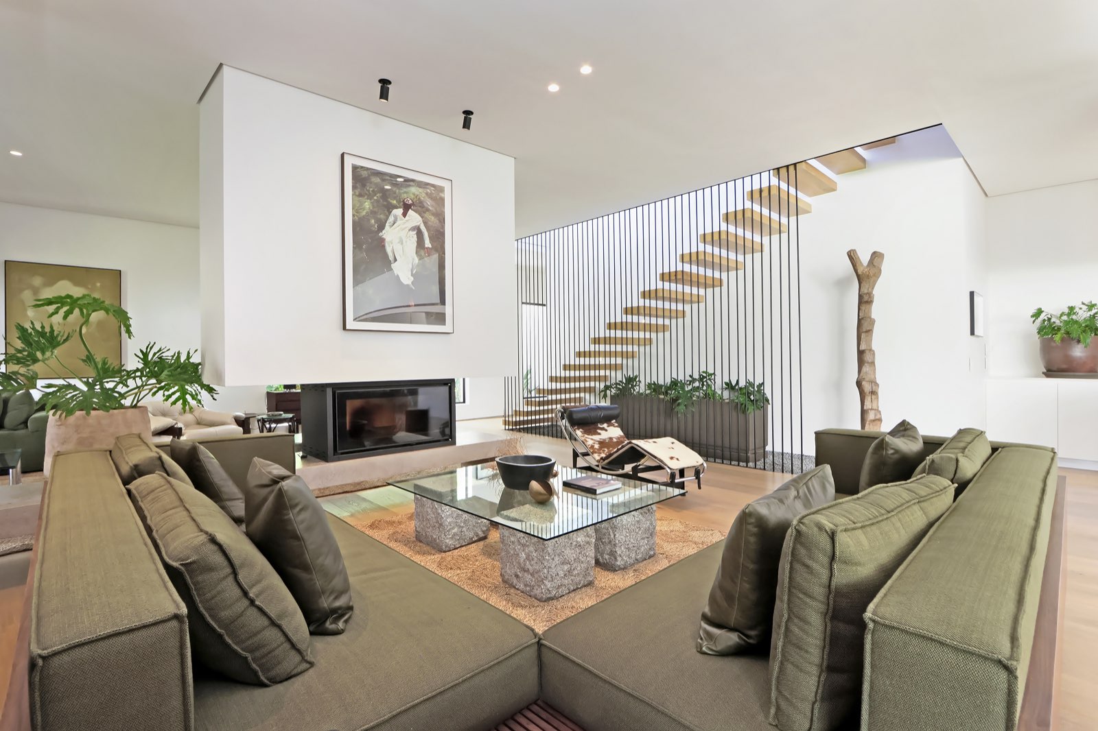 Green sectional sofa, fireplace, floating staircase