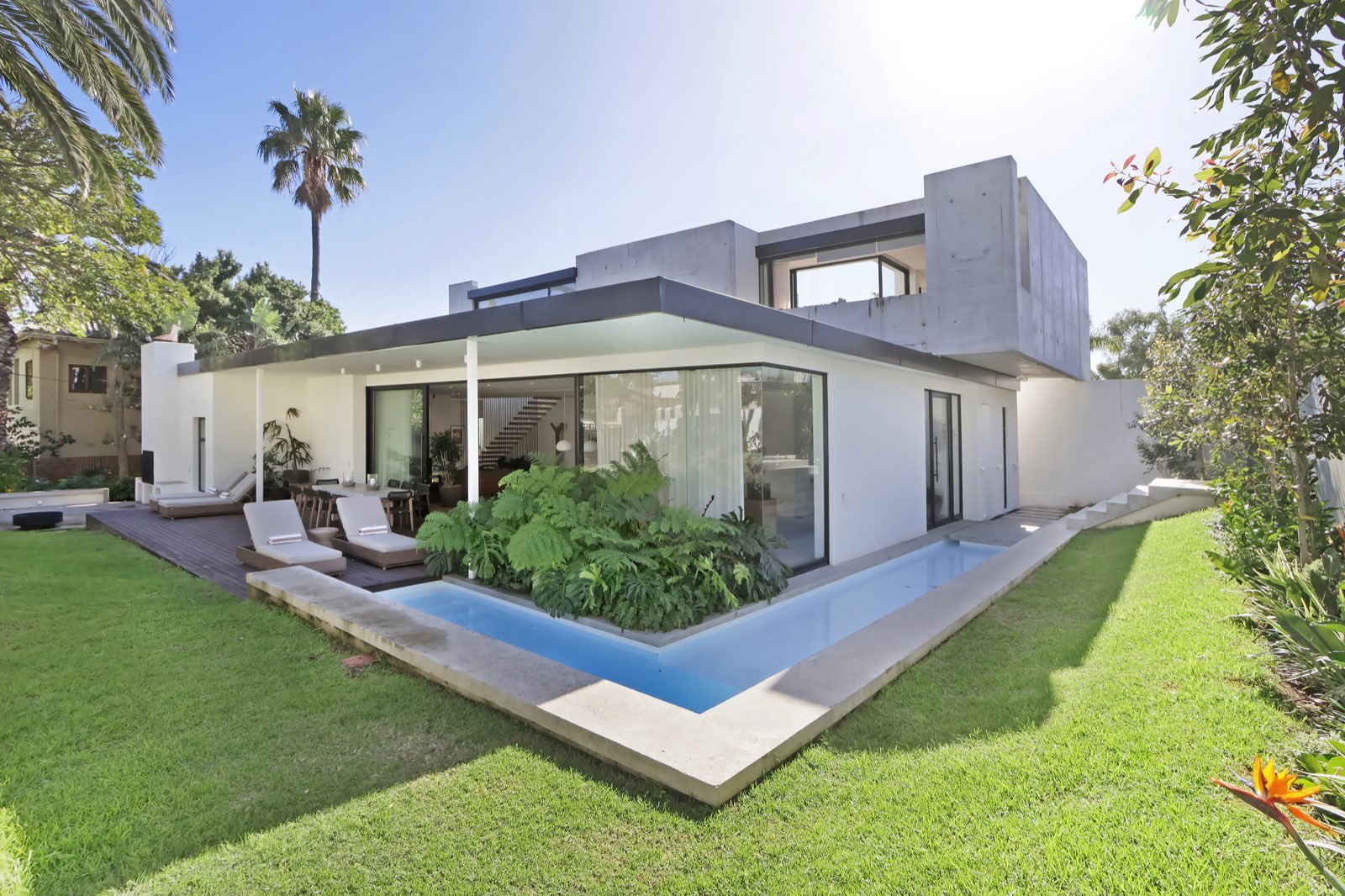 Full facade with L-shaped pool and tropical garden