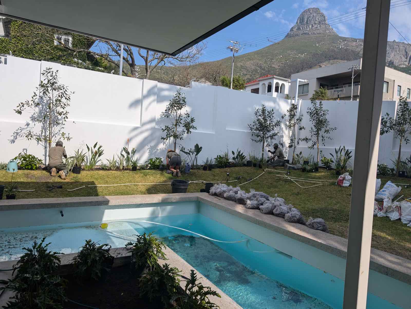 The crew finishing the garden under Lion's Head — rubble bags still stacked along the pool